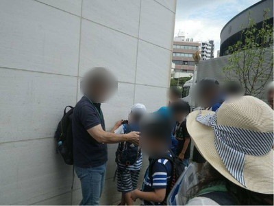 白い壁の石材を観察する親子